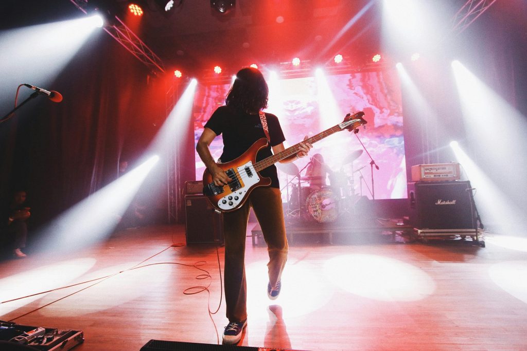 Energetisches Rockkonzert mit einem Bassisten auf der Bühne und effektvoller Bühnenbeleuchtung.