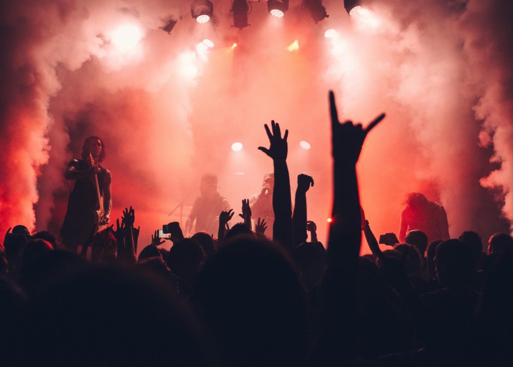 Dynamische Szene einer Rockband, die live vor einem begeisterten Publikum und mit stimmungsvoller Bühnenbeleuchtung auftritt.