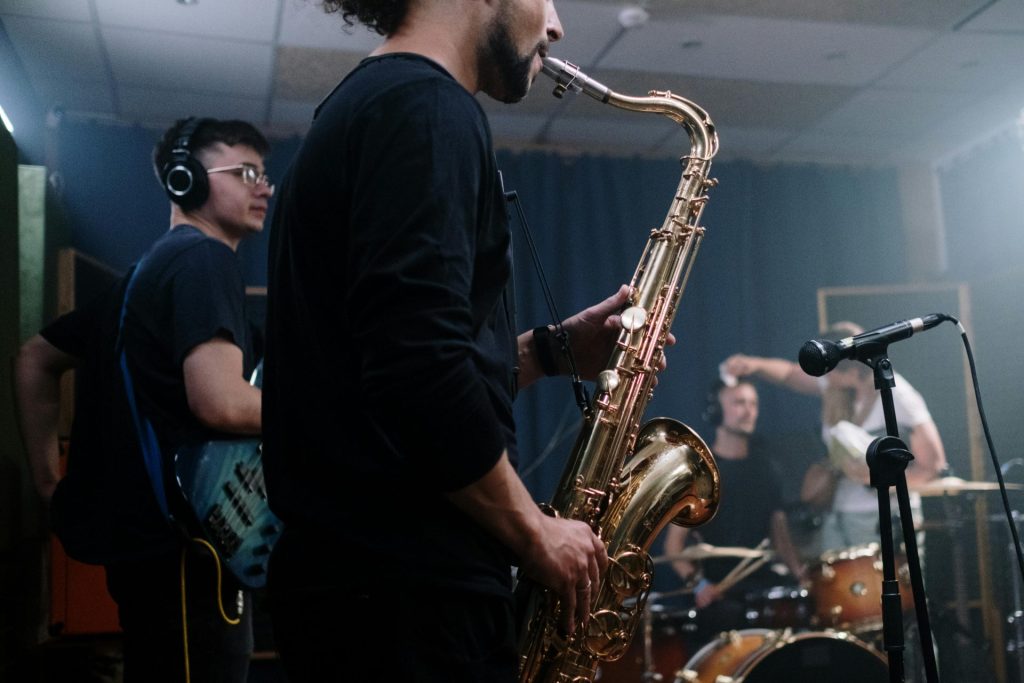 Musiker spielen Instrumente in einem Aufnahmestudio, der Fokus liegt auf dem Saxophonisten.