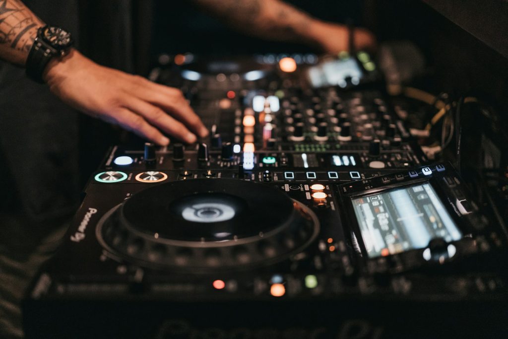 Person, die in einem Raum einen DJ-Controller bedient